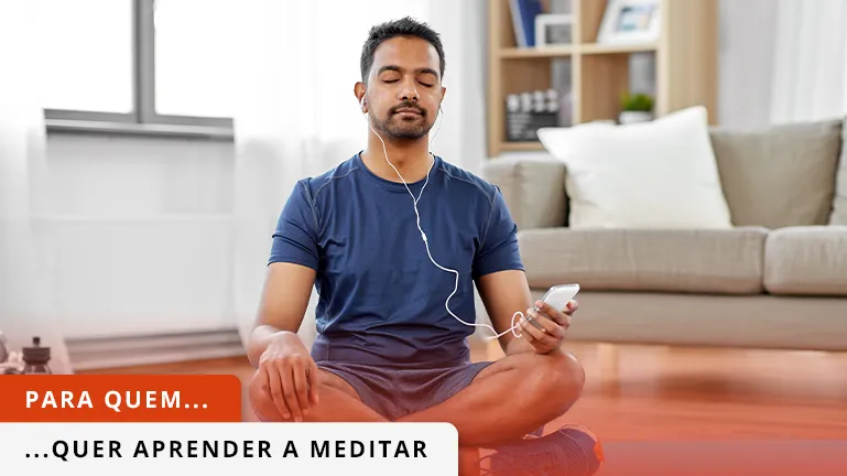 Mulher em roupas desportivas pretas, sentada com pernas à chinês, a meditar.