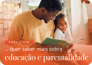 Pai a ler um livro ao filho, com ele aninhado ao colo.