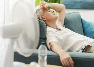 homem com calor a refrescar-se à ventoinha