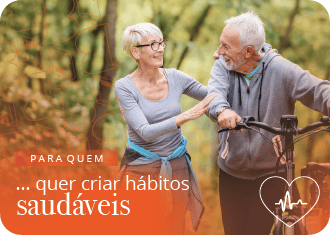 Dois idosos, com a senhora a abraçar o senhor, que leva uma bicicleta pelas mãos.