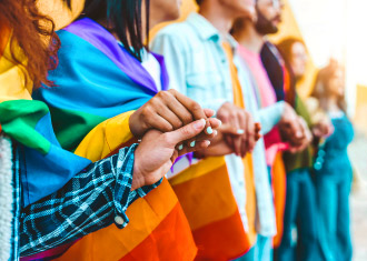 Várias pesoas a segurar uma bandeira LGBTQIA+