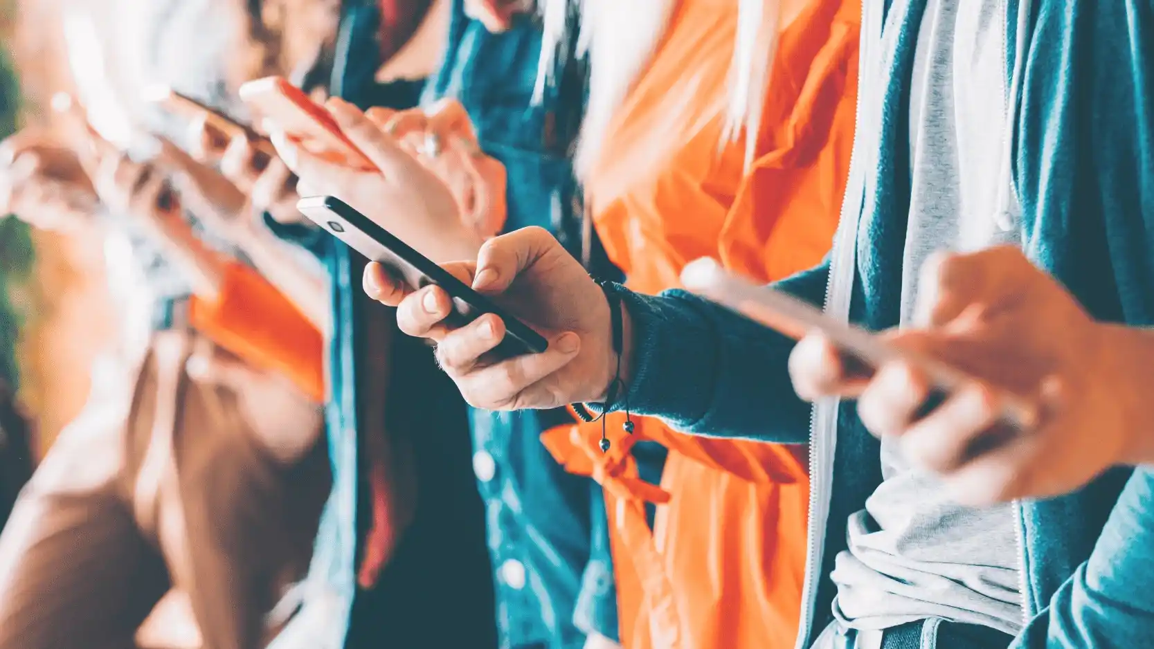Fotografia de vários jovens com smartphones na mão, a fazerem scroll