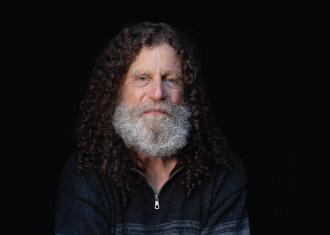 Fotografia do autor robert sapolsky, a usar uma camisola azul.